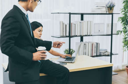Asian man boss pointing finger to a stressed woman employee in officeの写真素材