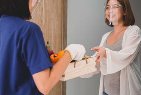 Close up hands woman receive paper bag food from delivery at home,Delivers takeaway mealの写真素材