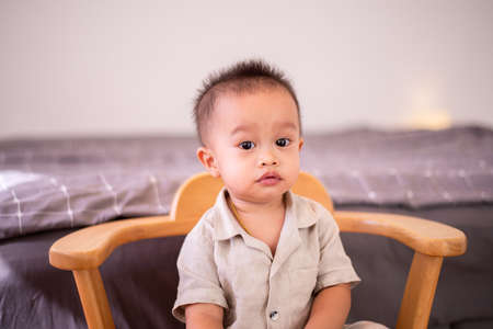 Adorable asian baby boy sitting on chair in bedroom,Happy new born kid looking to cameraの写真素材