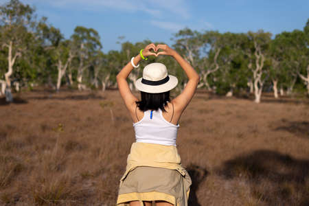 Happy traveller woman standing and showing hands heart shape at nature,Back viewの写真素材