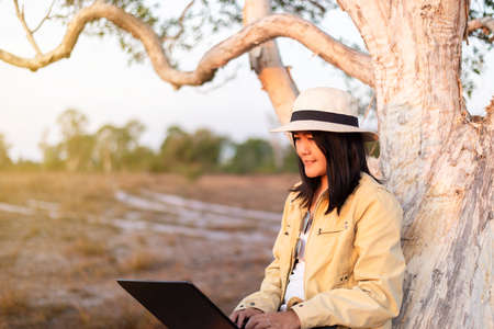 Solo traveller asian woman tourist using internet with laptop computer at forest,Travel and vacation conceptの写真素材