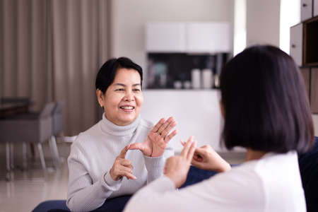 Sign language specialist talking with elderly patient deaf hearing and showing hand gesturesの写真素材