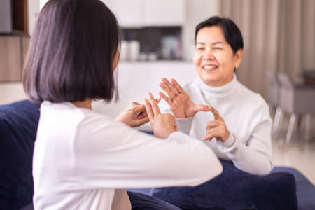 Sign language specialist talking with senior patient deaf hearing and showing hands gestureの写真素材