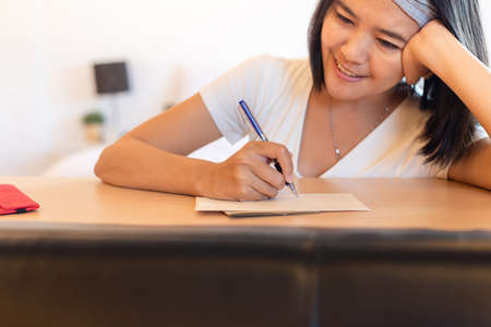 Happy asian woman writing greeting cards at home for next holidayの写真素材