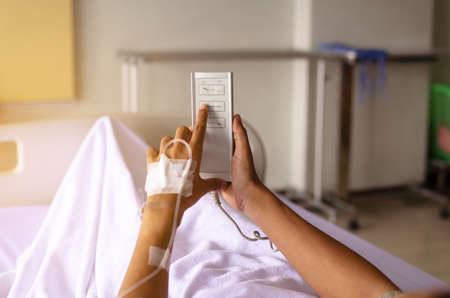 Patient hands using remote for adjustment level sick bed at hospitalの写真素材