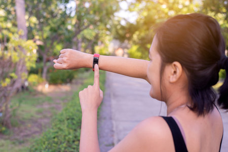 Sporty women using smart watch for running and checking device at outdoor during sunrise in the...
