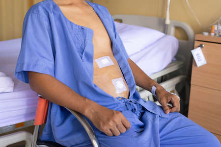 Patient man showing sticking plaster patched surgery wound on stomach after surgical