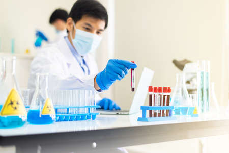 Doctor hands holding test tube with coronavirus blood test at laboratory,Covid-19の写真素材