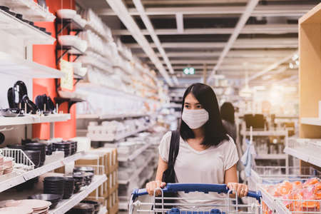Beautiful asian women wearing surgical face mask and shopping during virus outbreak in department...