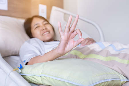 Patient asian woman showing hands ok sign on sick bed at the hospital,Health insurance conceptの写真素材