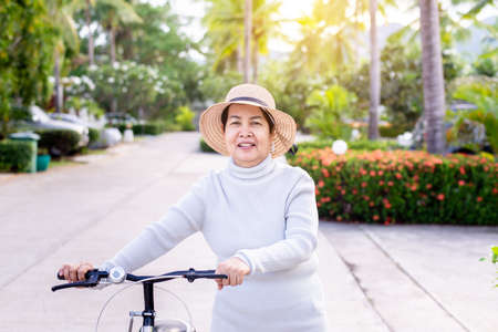 Happy senior asian woman cycling bicycle at park,Health insurance and elder care conceptの写真素材