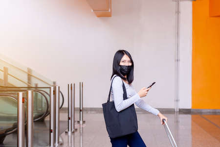 Asian woman wearing face mask and using mobile phone during coronavirus pandemic in the mallの写真素材