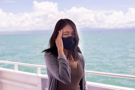 Woman suffering from sea sickness and feeling headache while on boatの写真素材