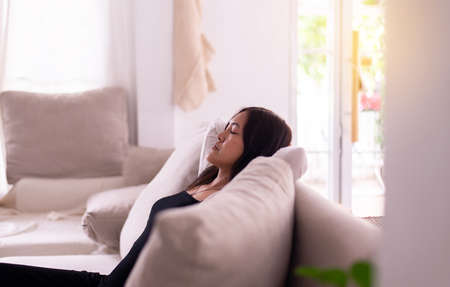 Happy asian woman take a nap while sitting on couch in living room with hands over head,Relax timeの写真素材