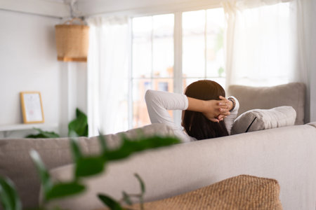 Happy woman sitting on couch in living room with hands over head,Relax timeの写真素材