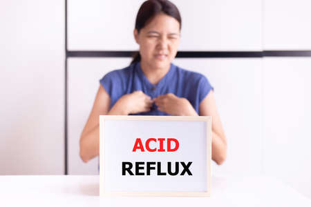 Woman having a gerd with the word reflux acid on whiteboard,Gastroesophageal reflux disease
