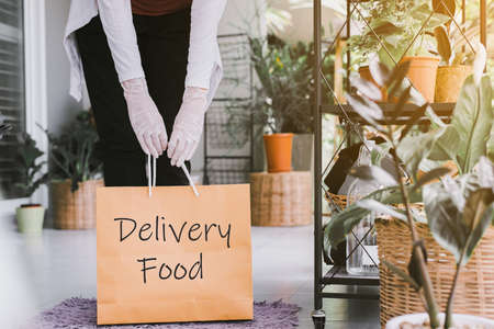 Woman hands holding takeaway food in paper bag from delivery service during virus pandemic situation...