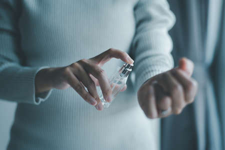Woman hands applying bottle of her favorite perfume at homeの写真素材