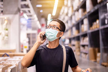 Asian man using mobile phone and shopping during virus outbreak in department storeの写真素材