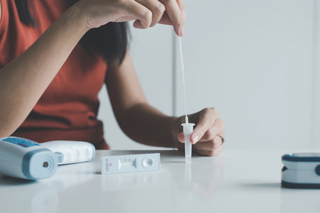 Patient woman using a self test rapid antigen testing kit at homeの写真素材