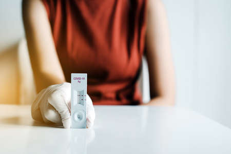 Patient woman showing result a self test rapid antigen testing kit at homeの写真素材