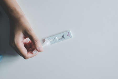 Patient woman showing result a covid-19 self test rapid antigen testing kit at home