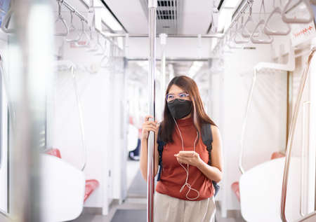 Happy woman listening to music with smart phone on subway train,Safety on public transportの写真素材
