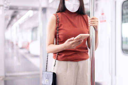 Woman wearing face mask and using mobile phone in subway train,Safety on public transport conceptの写真素材