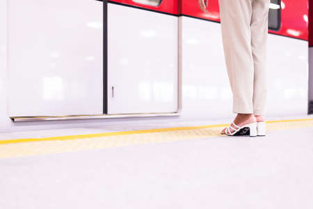 Woman standing behind safety yellow line for waiting for the train