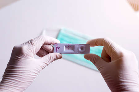 Patient woman showing result a covid-19 self test rapid antigen testing kit on white backgroundの写真素材