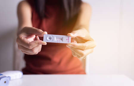 Patient hands showing result a covid-19 self test rapid antigen testing at home