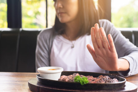 Hands woman refusing beef steak in restaurant,No meal,Vegetarian and vegan conceptの写真素材