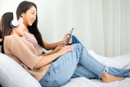 Two young asian women listening to music online at home together,Happy and smiling,Lesbian,LGBT...
