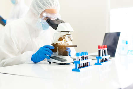 Doctor asian man using microscope with metal lens for research covid-19 disease in laboratory