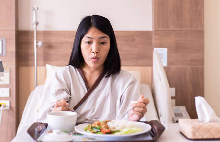 Asian woman patient eating meal on sickbed in the hospital