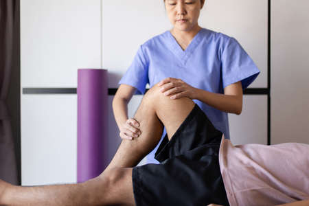 Physiotherapist women orthopedist examining with men patient in clinic,Physical therapy conceptの写真素材