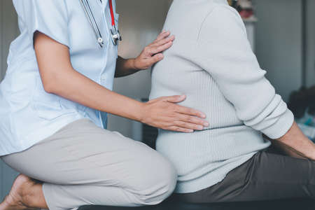 Physiotherapist doing treatment to senior woman patient in clinic ,Elderly women suffering from low-back lumbar pain,Physical therapy conceptの写真素材