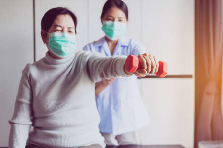 Physiotherapist training with senior women patient using dumbbell in hospital,Physical therapy...