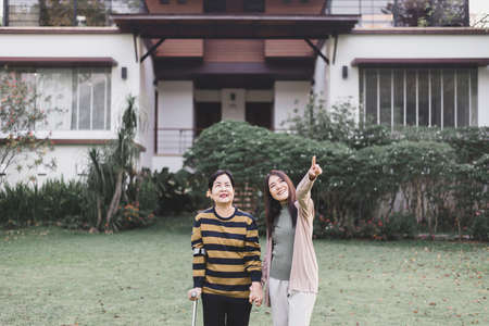 Caregiver take care to senior woman hand holding crutch try to walking at outdoor,Physical therapy conceptの写真素材