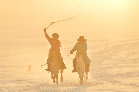 horse running, two horseman racing on the snow, chinaの写真素材