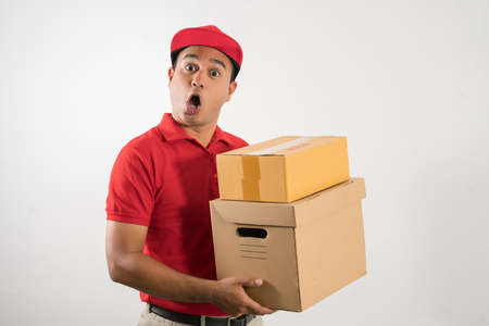 Red Delivery handsome asian man holding parcel cardboard box on isolated white background.の写真素材