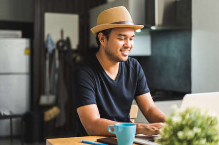 Social distancing concept. Asian handsome man work from home with laptop. Young Casual businessman aged around 30 using laptop for his work.の写真素材