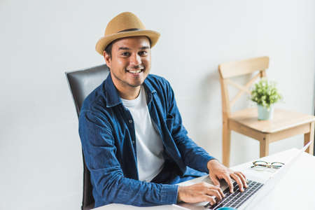 Social distancing concept. Asian handsome man work from home with laptop. Young Casual businessman...