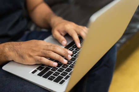 Close up male hands using laptop work from home sofa