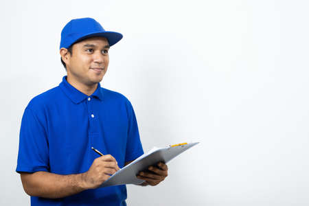 Asian Delivery man signing clipboard receipt of delivery package on isolated white background.