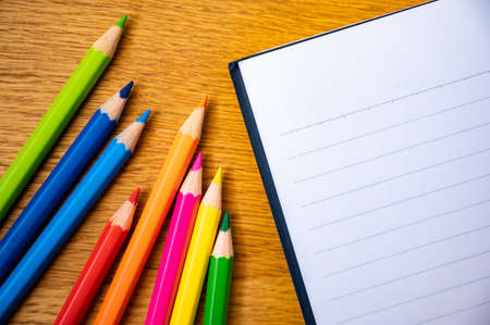 Education background concept. Color pencil on the wooden table with note book.