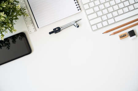 Top view table desk of office architect pencil, compasses tool, ruler, rubber, protractor grid, sharpener, glasses, smartphone, keyboard with copy space background.の写真素材