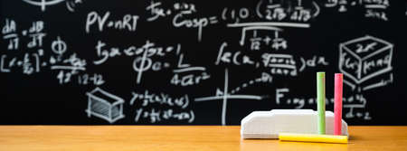 Education background concept. Board eraser and chalk on the wooden table with blackboard with many...