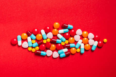 A lot of pill on the red background. Medicine pills, tablets and capsules.の写真素材