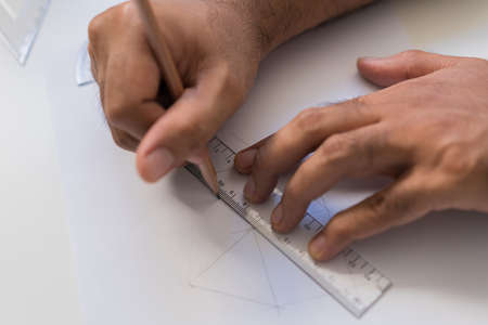 Work from home concept. Close up male hands is painting picture with  pencil in the paper on white...
